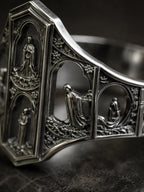Macro detail of the Saints Prayer ring's miniature cathedral facade and saint reliefs in oxidized silver