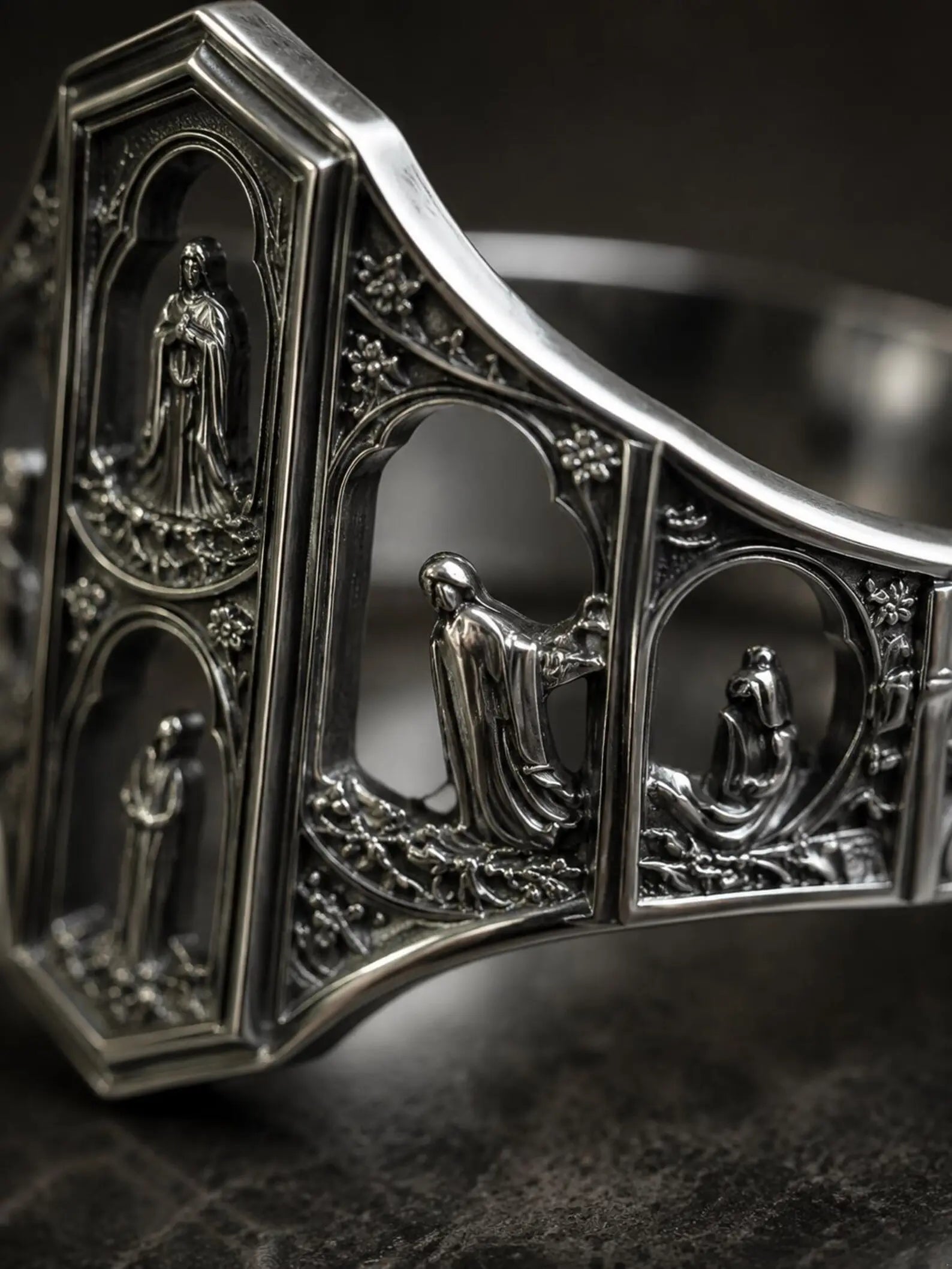 Macro detail of the Saints Prayer ring's miniature cathedral facade and saint reliefs in oxidized silver