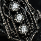 Close-up of an ornate metal object with three diamonds embedded in it. moissanite, Victorian, oxidized silver