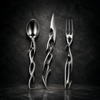 Cyber Baroque gothic-futurist cutlery set — mirror-polished spoon, knife and fork with biomorphic thorn handles on a dark wall