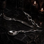 Gothic-futurist luxury flatware set styled on black marble with candlelight — sterling silver spoon, fork and knife