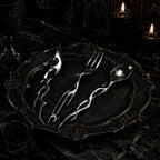 Cyber Baroque spoon, fork and knife arranged on an ornate dark baroque charger plate